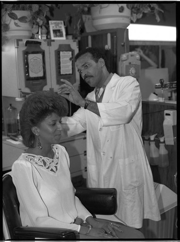 African American hairdresser styling his client's hair, Los Angeles, 1984