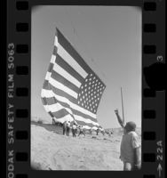 Rancher Bob Older watching unfurling of 67x102 foot American flag for U.S. bicentennial in Oro Grande, Calif., 1976