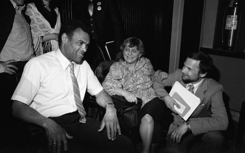 Paul Robeson Jr. talking with a woman and man in a hallway or foyer, Los Angeles, 1982