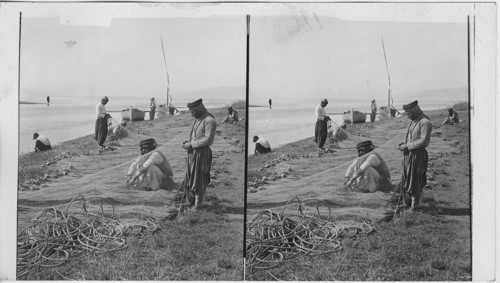 Fishermen mending nets at Jordan’s entrance to Sea of Galilee. Palestine