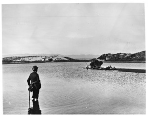 Well dressed gentleman standing knee deep in Playa del Rey lagoon, looking east, ca.1902