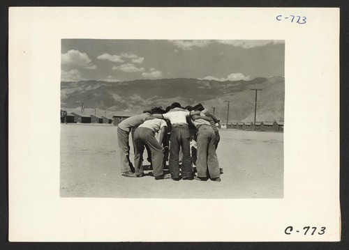 Manzanar, Calif.--Baseball players in a huddle. This game is very popular with 80 teams having been formed throughout the Center. Most of the playing is in the wide fire-break between blocks of barracks. Photographer: Lange, Dorothea Manzanar, California