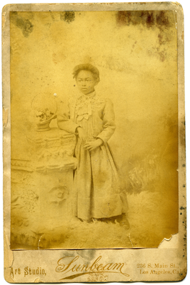 Portrait of unidentified girl standing with her right arm resting on a pillar