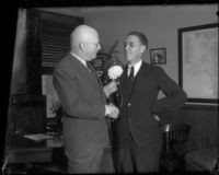 Supervisors John Anson Ford and Harry M. Baine shake hands and exchange a flower, Los Angeles, 1930s