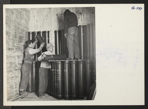 Three evacuees unloading prop charges from a box car at the Sioux depot. The prop charges are placed on a truck and transported to a storage place at the depot. Photographer: Aoyama, Takashi Sidney, Nebraska