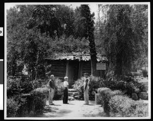 Three boys in front of an old log cabin brought by Elias J. Baldwin to Rancho Santa Anita from his father's home, ca.1940