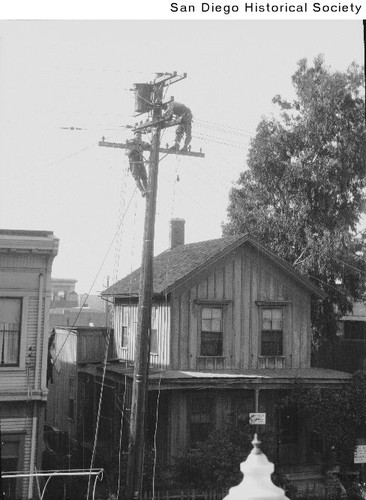 Men working on a telephone pole in a residential area