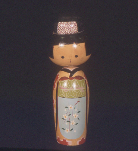 Kokeshi doll with white flowers and blue background