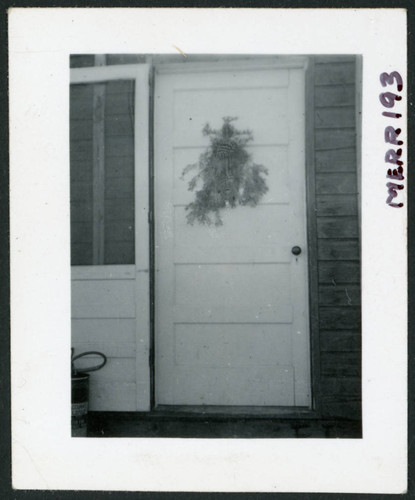 Photograph of a front door at Cow Creek Camp with a pine bough decoration