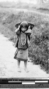 Child carrying a basket behind her head, Philippines, ca. 1920-1940