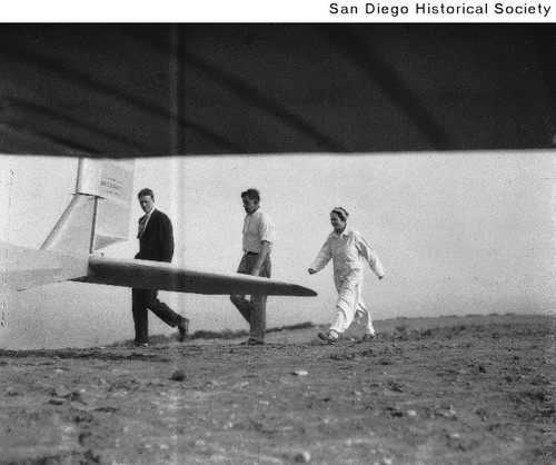 Charles and Anne Lindbergh walking with another man behind a airplane on Mount Soledad