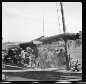 Dock workers unloading rice from a skiff in China, ca.1900