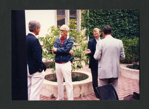 Four male colleagues conversing at Betty Merfeld's retirement party, Scripps College