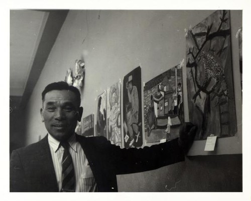 Man posing along a wall of paintings