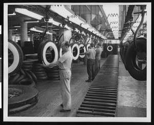 Three factory workers inspecting tires, ca.1950