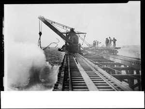 Construction of the San Pedro breakwater from railroad tracks over the ocean, ca.1899