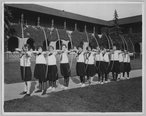 Archery students pose with bows and arrows in the San Jose quad, ca. 1925