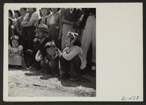 Manzanar, Calif.--Evacuees of Japanese ancestry watching Memorial Day services. Evacuee Boy Scouts took a leading part in the ceremonies held at this War Relocation Authority center. Photographer: Stewart, Francis Manzanar, California