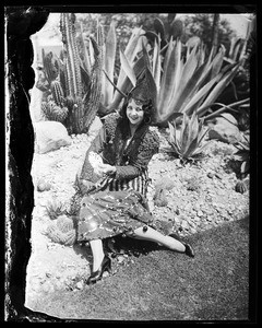 lone woman in a costume sitting by a desert scene, in Los Angeles