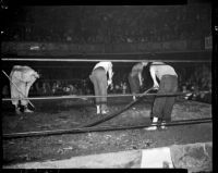 Workers prepare ankle-deep mud in the ring for a wrestling match between Sandor Szabo and Prince Bhu Pinder at Olympic Auditorium, Los Angeles, October 20, 1937