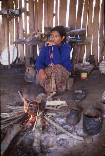 Guatemalan refugee sits in front of a fire, Cuauhtémoc, 1983