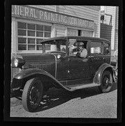 Man driving car in front of General Painting Contractor building, California Labor School