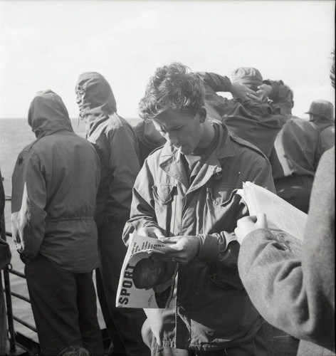 Serviceman with sports magazine of the USS Meigs