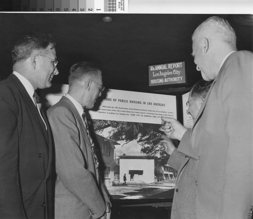 Photograph of municipal officials posing in front of exhibit for 10th Annual Report of the Los Angeles City Housing Authority