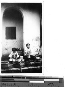 Two children washing bowls at Dongshi, China, 1937