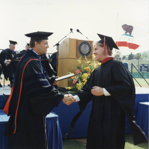 President Davenport presenting a diploma to a male student