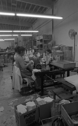 Women at their workstations sewing white gloves in a workshop, Los Angeles