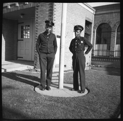 Two Oakland firefighters standing in front of fire station