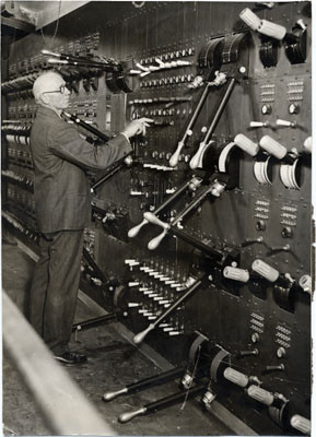 [Master electrician Charles Holzmueller standing next to the electrical switchboard at the War Memorial Opera House]