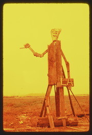 AUG75P4-22: hitchhiker holding LA sign sculpture, orange filter