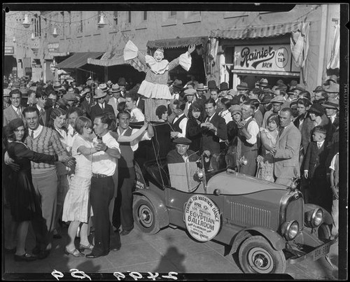 Clown on stilts among crowd of dancing couples, advertising dance marathon, Santa Monica, 1928