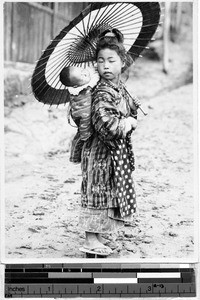 Japanese girl carrying a baby and an unbrella, Japan, ca. 1932