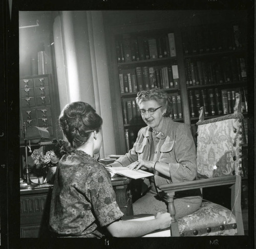 Dorothy Drake reads to a student at her desk in Denison Library, Scripps College