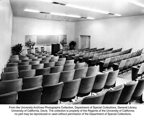 Everson Hall, Auditorium, Home Economics Building, Davis. The 200-seat auditorium in the new Home Economics Building on the Davis campus of the University of California for class lectures and conferences. It is equipped with an electrically operated screen for moving pictures and slides. Each seat has a writing arm that folds down the front of the arm-support when not in use. Through the right rear door is equipment storage room for special lecture demonstrations. Such items as mobile cabinets equipped with sinks are stored here. They can be moved into the front of the auditorium and hooked up to fixtures recessed in the floor. The auditorium has its own heating and air conditioning units separate from the rest of the building