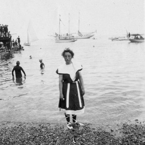 Woman, swimmers and boats share the beach