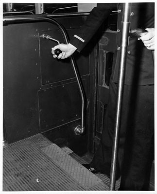 [Man demonstrating reverse lever on a streetcar]