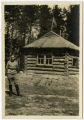 Mini photo of man standing in front of log cabin