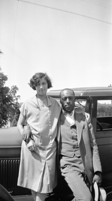 Man and woman standing next to automobile