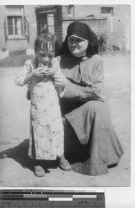 Maryknoll sister with a hungry orphan at Fushun, China, 1937