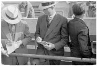 Sports officials writing down times at a track meet between UCLA and USC, Los Angeles, 1937