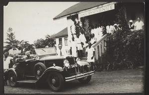Empfang von Dr. Ernst Pfleiderer vor dem Basel Missions Hospital in Agogo, 1. Aug. 1932. Dr. Huppenbauer im Auto im Hintergrund die Angestellten