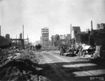 [View of ruins and rubble, looking north along Kearny St. Telegraph Hill in distance]