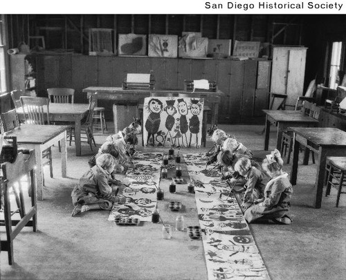 Children at Francis Parker School painting pictures while sitting on the floor of a classroom