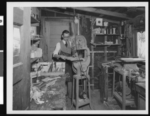 Man working in a small woodshop with machinery, ca.1930