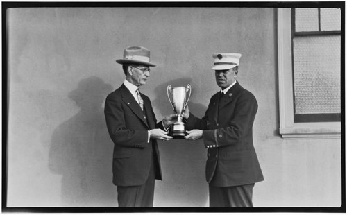 Official presenting trophy to unnamed captain