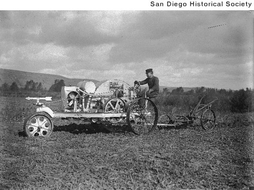 A man at the wheel of a three-wheeled Bull Gas Tractor